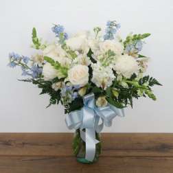 White and blue mixed bouquet in a glass vase with a pale blue ribbon