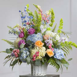 Colorful mixed flower arrangement in a white wicker basket