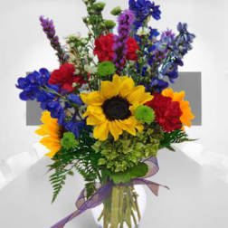 Mixed bouquet with sunflowers, roses, and blue flowers in a glass vase