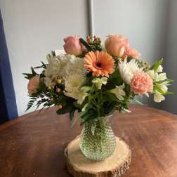 Mixed bouquet in a glass vase on a wood slice