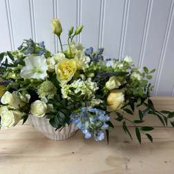 Mixed bouquet of white, yellow, and blue flowers in a white vase