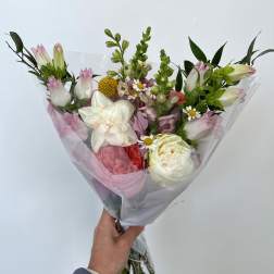 Handheld bouquet of pink and white flowers wrapped in clear plastic