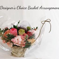 Basket arrangement of pink and peach flowers wrapped in clear plastic