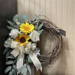 Floral wreath with yellow and white flowers and a large ribbon