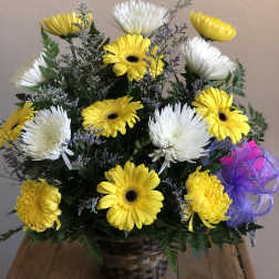 Yellow and white daisy bouquet in a woven basket with a purple ribbon