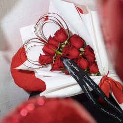 Bouquet of red roses wrapped in white paper with a red ribbon
