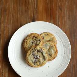 Three chocolate chip cookies on a white plate