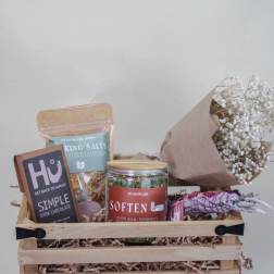 Gift basket with chocolates, bath salts, tea, and a small bouquet of white baby's breath