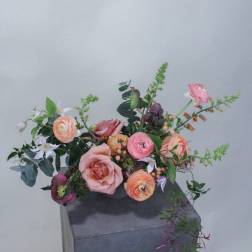 Loose pastel bouquet in a tall dark vase with pink and peach blooms