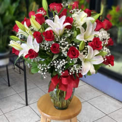 Red roses and white lilies in a glass vase with a red ribbon