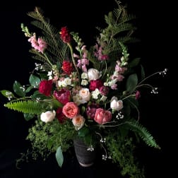 Tall mixed bouquet in a dark vase with pink and white blooms
