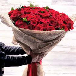Large bouquet of red roses wrapped in burlap with a red ribbon