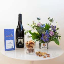 Flower arrangement with wine, chocolates, and nuts on a table