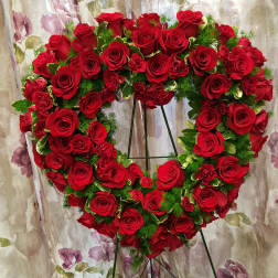 Heart-shaped wreath of red roses on a metal stand