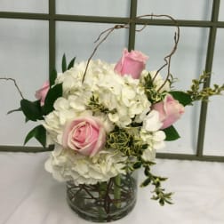 Pink roses and white hydrangeas arranged in a glass vase