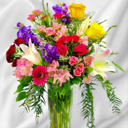 Mixed bouquet of roses, lilies, and pink flowers in a glass vase