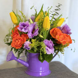 Bouquet of orange roses, purple lisianthus, and yellow tulips in a purple watering can