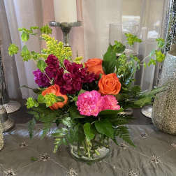 Mixed bouquet of orange and pink flowers in a clear glass vase