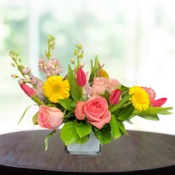 Pink roses and yellow daisies in a square glass vase