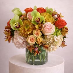Mixed bouquet of roses, hydrangeas, orchids, and chrysanthemums in a glass vase