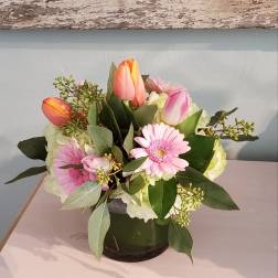 Pink gerbera daisies and tulips in a glass vase