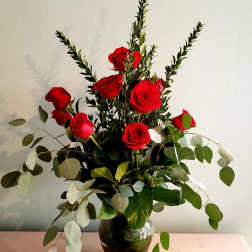 Red roses arranged in a dark glass vase with airy eucalyptus