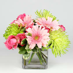 Pink roses and gerbera daisies in a clear square vase