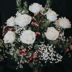 White roses arranged with pink berries and baby's breath
