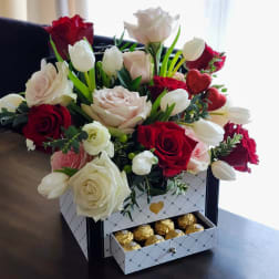 Bouquet of red and white roses with white tulips in a gift box with chocolates