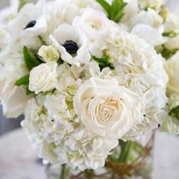 White roses and hydrangeas arranged in a clear glass vase.