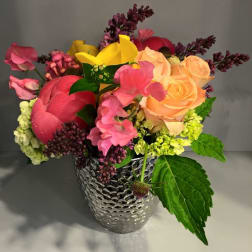 Colorful bouquet of roses, calla lilies, and mixed blooms in a silver vase