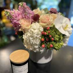 Bouquet of pink and white flowers in a white vase beside a candle