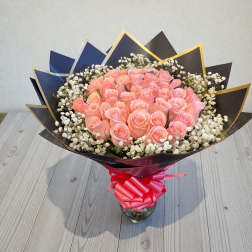 Bouquet of pink roses with baby's breath in a glass vase