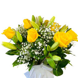 Yellow roses and lilies in a wrapped bouquet with baby's breath
