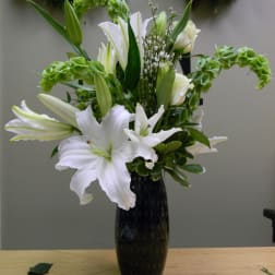White lilies arranged in a tall black vase