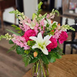 Bouquet of pink roses, white lilies, and pink snapdragons in a glass vase