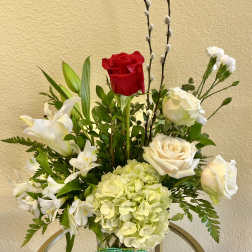 Mixed bouquet with red and white roses, lilies, and pale hydrangea in a glass vase