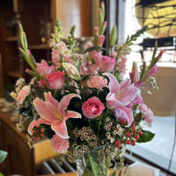 Pink lilies and roses arranged in a glass vase