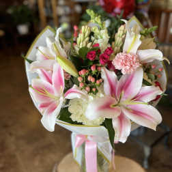 Pink and white lily bouquet with roses and carnations in a glass vase