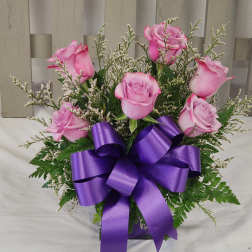 Pink roses arranged with a purple ribbon bow