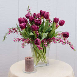 Magenta tulips in a clear glass vase with pink filler flowers