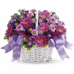 Purple and pink daisy bouquet in a white basket with lavender ribbons