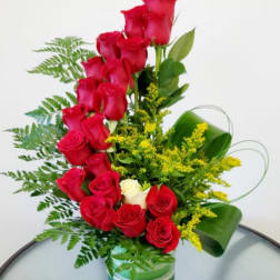 Red roses arranged in a clear glass vase with yellow filler flowers