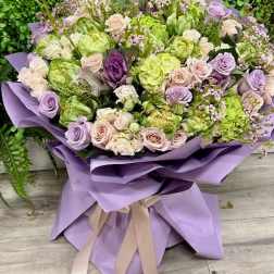 Lavender and green bouquet of roses wrapped in purple paper