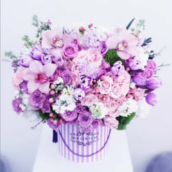 Large pink and purple flower arrangement in a striped hat box