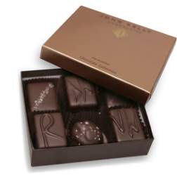 Open brown box of assorted dark chocolates with decorative toppings