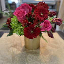 Pink roses and red gerbera daisies in a gold vase