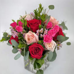 Bouquet of red, pink, and blush roses in a clear glass vase