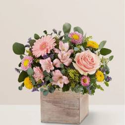Pink and yellow mixed flower arrangement in a wooden box