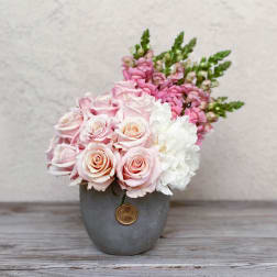 Pink and white roses arranged in a gray vase
